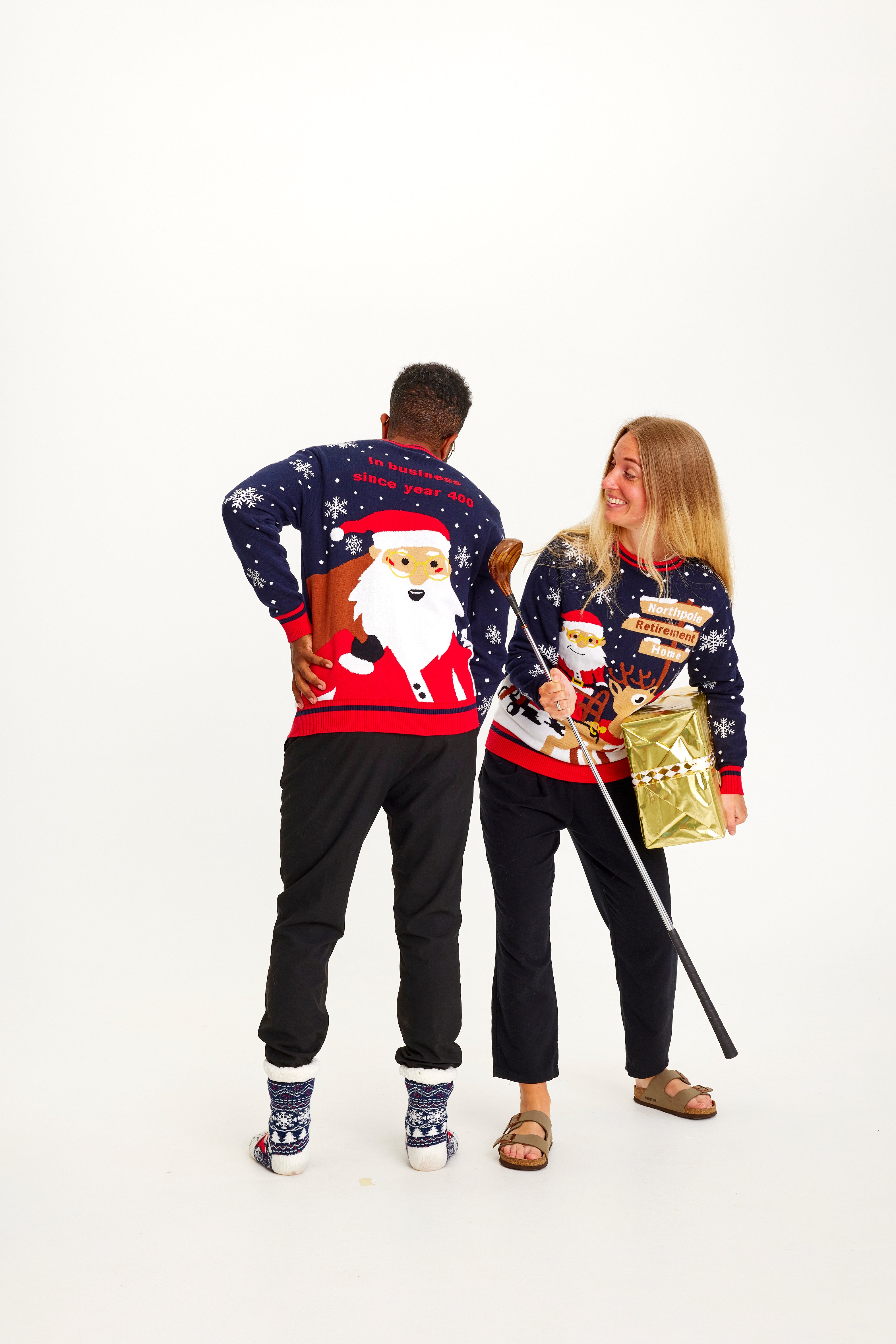 En mand og en kvinde med en gave i hånde er begge iklædt samme julesweater.